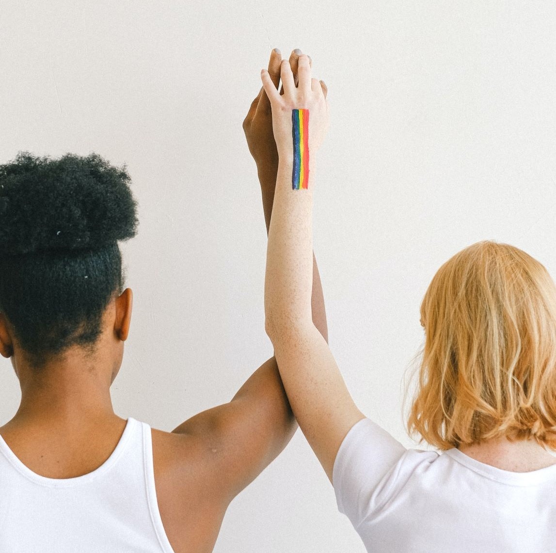 Two People Holding Embraced Hands, One with Rainbow Pride Flag